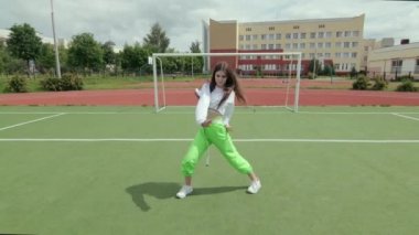 Güzel kız dans ediyor ve modern koreografi yapıyor, sokak dansı yapıyor, poz veriyor, sokak tarzı kıyafetlerle serbest dans ediyor. Gimbal atışı. Yavaş çekim