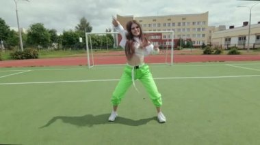 Genç dansçı, modern dans gösterisi yapıyor. Sportsground 'da sokak dansı yapıyor. Hip hop ve break dans tekniği öğrenme kavramı. Gençlik alt kültürü. Gimbal atışı. Yavaş çekim