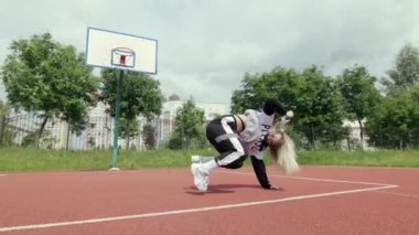 Eşofmanlı, uzun saçlı enerjik genç bir kız dans salonu twerk dansı, modern sokak dansı, açık havada kalçalarını sallıyor. Seks Dansı. Gimbal atışı. Yavaş çekim