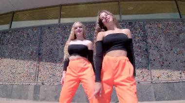 Çağdaş dans eden iki genç bayanın düeti, binanın karşısında dans salonu twerk 'i. Seks Dansı. Şehirde serbest dans yapan bir şehir. Gimbal atışı.