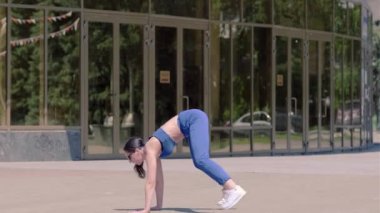 Uzun saçlı, eşofmanlı, sokak dansı yapan modern dansçı, dans salonu twerk 'i aynalı camla kalçalarını sallayan genç bir kadın. Seks Dansı. Şehirde şehir dansı serbest stil