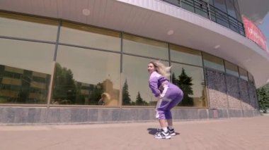 Uzun saçlı, dans eden, modern koreografiyi icra eden sokak dansı yapan, sokak tarzı kıyafetlerle poz veren, serbest dans eden genç bir kadın. Gimbal atışı. Yavaş çekim