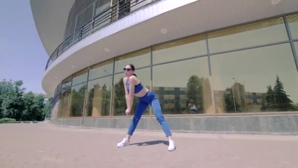 穿着运动服的年轻女子跳着现代舞步 舞厅舞曲着 用镜像的玻璃摇着对面的臀部 布迪舞曲城市里的自由式舞蹈 Gimbal Shot — 图库视频影像