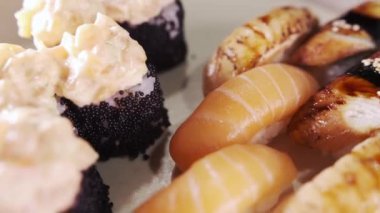 Suşi ve rulo ile tabağa yakın çekim. Restoran mutfağı. Japon yemeği. Kaypak hareket ediyor. Makro görünüm