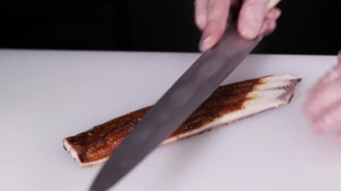 Şefin önden görünüşü eldivenli elleri Japon suşi ruloları yapıyor, füme yılan balığı kesiyor. Restoran mutfağı. Japon yemeği.