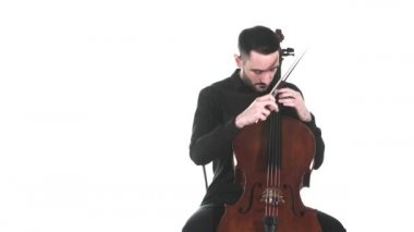Siyah tişörtlü genç yakışıklı adam klasik çello çalıyor. Pizzicato tekniği. Senfonik müzik konseri. İzole edilmiş. Orta uzunlukta.