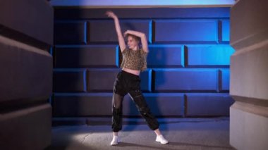 Genç kız dansçı modern sokak dansını gecenin geç saatlerinde duvara karşı yapıyor. Çağdaş koreografi. Gençlik alt kültürü