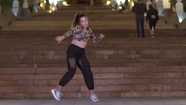 ヒョウTシャツの精力的な若い女性が夜に古い巨大な石の階段の前で屋外でストリートダンスを踊る コンテンポラリー振付 — ストック動画