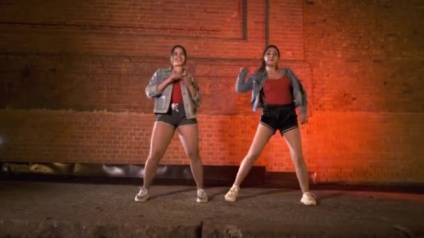 Två Lyckliga Flickor Dansar Modern Koreografi Streetdance Mot Tegelvägg Natten — Stockvideo