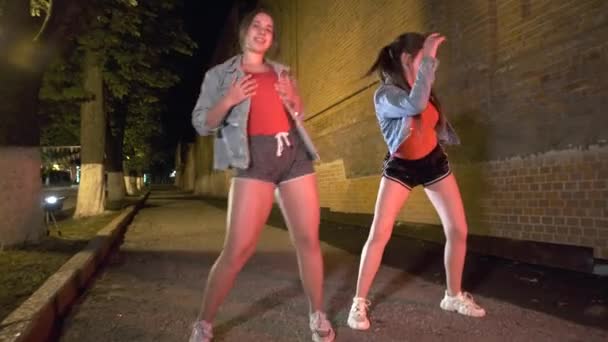 2人の少女が夜市公園でストリートダンスを踊ります 若いサブカルチャーだ コンテンポラリー振付 ジンバルショット — ストック動画