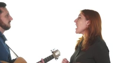 Genç müzisyenlerin düeti. Sakallı bir adam akustik gitar çalar, kızıl saçlı bir kadın şarkı söyler. Beyaz arka plan. İzole edilmiş