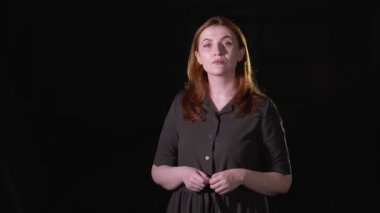 Güzel kızıl saçlı kız şarkı söylüyor. Siyah arka plan. İzole edilmiş. Orta uzunlukta.