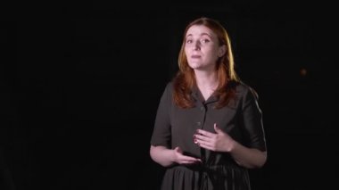 Kızıl saçlı genç ve güzel bir şarkıcı güzel bir melodi çalar. Siyah arka plan. İzole edilmiş. Orta uzunlukta.