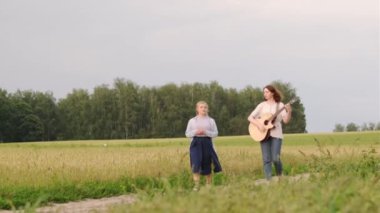 İki güzel genç kız bir yaz akşamında gün batımında bir buğday tarlası boyunca yürür ve şarkı söyler. Kız gitara eşlik ediyor.
