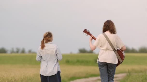 Dwie Młode Dziewczyny Gitarą Ukulele Spacerują Drodze Polu Pszenicy Zachodzie — Wideo stockowe