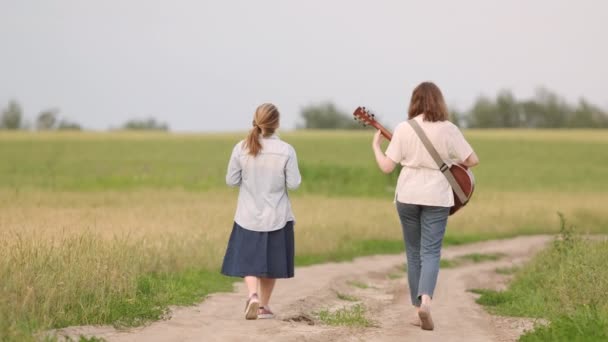 Two Young Girls Guitar Ukulele Walking Road Wheat Field Sunset — Stock Video