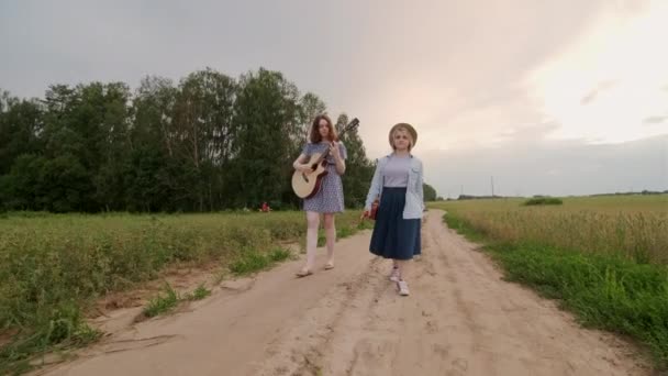 Zwei Junge Frauen Gehen Und Singen Einem Sommerabend Bei Sonnenuntergang — Stockvideo