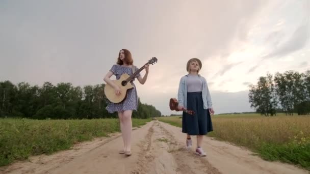 Две Молодые Женщины Ходят Поют Вдоль Дороги Вдоль Пшеничного Поля — стоковое видео