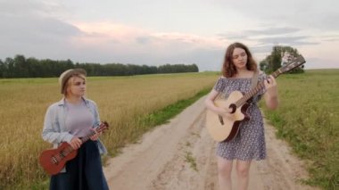 Sevimli, neşeli kızlar düeti. Yaz akşamları gün batımında buğday tarlası yolu. Gitar ve gitar. Kızlar şarkı söyler ve güler. Dinamik kamera hareketi. Yavaş çekim görüntüleri