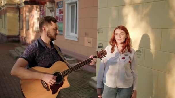 夏夜黄昏时分 一位吉他手和一位红头发歌手在城市街道上的二重唱 — 图库视频影像