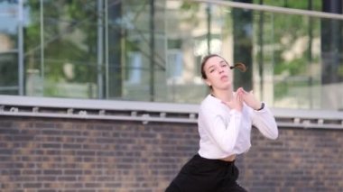 Genç dansçı kız binanın arka planında hip hop dansı yapıyor. Modern gençlik dansının olağanüstü unsurlarını sergiliyor.