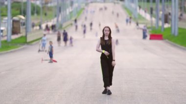 Kız sokakta dans ediyor. Arka planda insanların bulanık siluetleri görülüyor. Hip hop. Çağdaş koreografi. Yaz akşamı. Güneşli gün batımı. Yavaş çekim