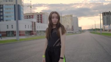 Geniş bir caddede dans eden genç ve güzel bir kadın. Yaz akşamı. Güneşli gün batımı. Hip hop. Çağdaş koreografi. Ağır çekim. Gimbal atışı.