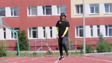 Eşofmanlı genç bir kız dansçı ve sokak dansı yapan bir şapka, Sportsground 'da hip hop yapan. Modern gençlik dansının olağanüstü unsurlarını sergiliyor. Yavaş çekim