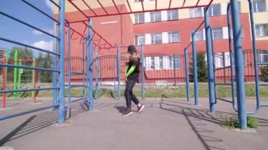 Sportsground 'da eşofmanlı ve şapka dansı yapan neşeli genç bir kadın. Şehirde serbest dans yapan bir şehir. Gençlik alt kültürü