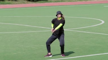 Genç kız bir stadyumda açık havada karmaşık akrobatik figürler sergiliyor. Hip hop. Şehirde serbest dans yapan bir şehir. Gençlik alt kültürü. Çağdaş koreografi. Yavaş çekim