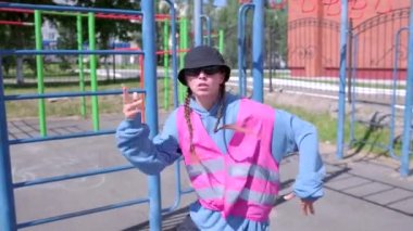 Spor sahasında eşofman ve şapka giyen hip hop yapan genç bir kadın. Yavaş çekim