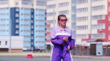 Renkli örgülü komik kız arka planda hip hop dansı yapıyor, neşeyle zıplıyor ve kameraya bakıyor. Yavaş çekim