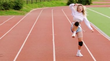 Stadyum koşu bandında dans eden genç ve güzel bir sarışın. Kalçalarını hareket ettiriyor. Yavaş çekim