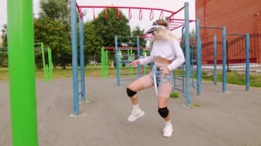 Kısa şortlu dansçı kız spor salonunda dans ediyor. Modern gençlik dansının olağanüstü unsurlarını sergiliyor. Yavaş çekim