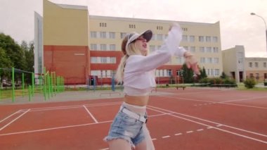 Şehir stadyumunda uzun saçlı muhteşem genç bayan twerk dansı yapıyor. Yavaş çekim
