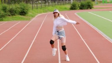 Stadyum koşu bandında dans eden genç ve güzel bir sarışın. Kalçalarını hareket ettiriyor. Yavaş çekim