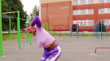 Güzel, genç esmer, uzun saçlı, spor sahasında popo dansı yapan. Yavaş çekim