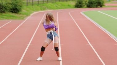 Stadyum koşu bandında dans eden genç ve güzel bir sarışın. Kalçalarını hareket ettiriyor. Yavaş çekim