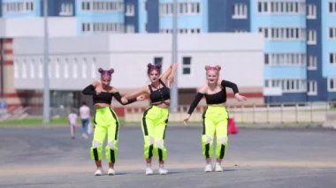 Üç güzel kız sokak dansı yapıyor, yüksek binaların arka planında hip hop koreografisi yapıyor. Yavaş çekim