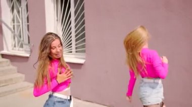 Kısa şortlu, serbest stil sokak dansı yapan, merdivenli bir binanın önünde hip hop koreografisi yapan neşeli genç kızların düeti. Yavaş çekim