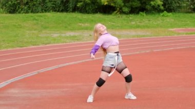 Dans pistinde dans eden genç, güzel sarışın kadın. Stadyumda dans eden elementlerle. Yavaş çekim
