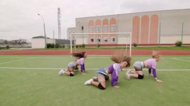 Uzun saçlı, kısa şortlu ve stadyumda dans eden bir grup neşeli genç kadın. Kalçalarını hareket ettiriyor.. 