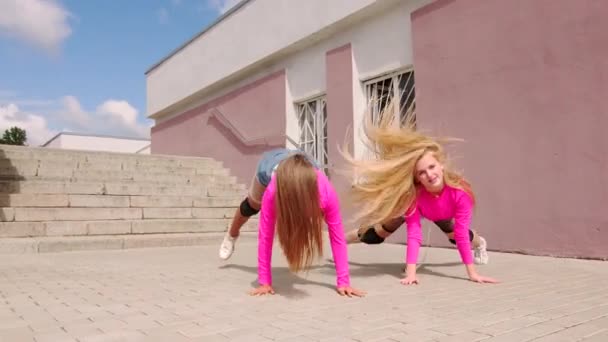 身着短裤的年轻而快乐的姑娘们在一座有楼梯的建筑物前跳舞 慢动作 — 图库视频影像