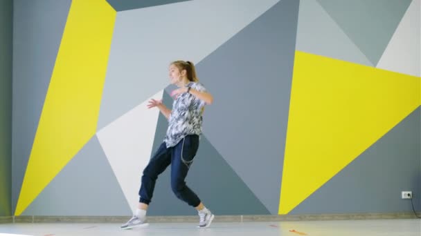 陽気若いです女の子ダンスヒップホップでザ スタジオで壁の前に明るい幾何学模様 — ストック動画