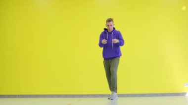 Stüdyoda sarı bir duvarın arkasında dans eden yakışıklı adam. İzole edilmiş.