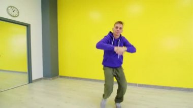 Sarı duvar arkasında hip hop dansı yapan genç adam..