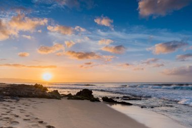 Günbatımı Sunset Beach Kuzey Shore Oahu, Hawaii kumlu plajda mercan kayaların üzerinden haddeleme sörf ile üzerinde