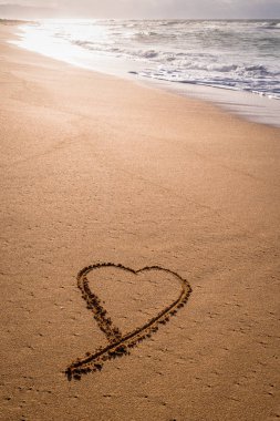 Kuma sahilde günbatımı dalgalar içinde yıkama ile çizilmiş kalp