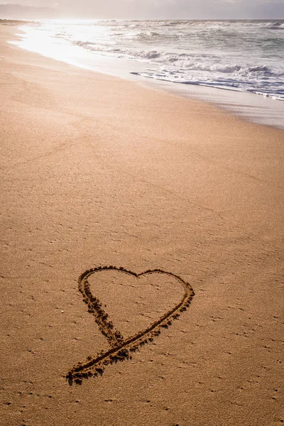 Kuma sahilde günbatımı dalgalar içinde yıkama ile çizilmiş kalp
