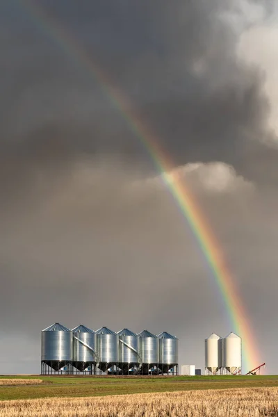 Rainbow over grain bins during spring storm on the prairies in Saskatchewan